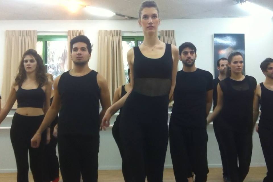 קבוצה בבגדי אימון שחורים בתרגול תנועה בסטודיו