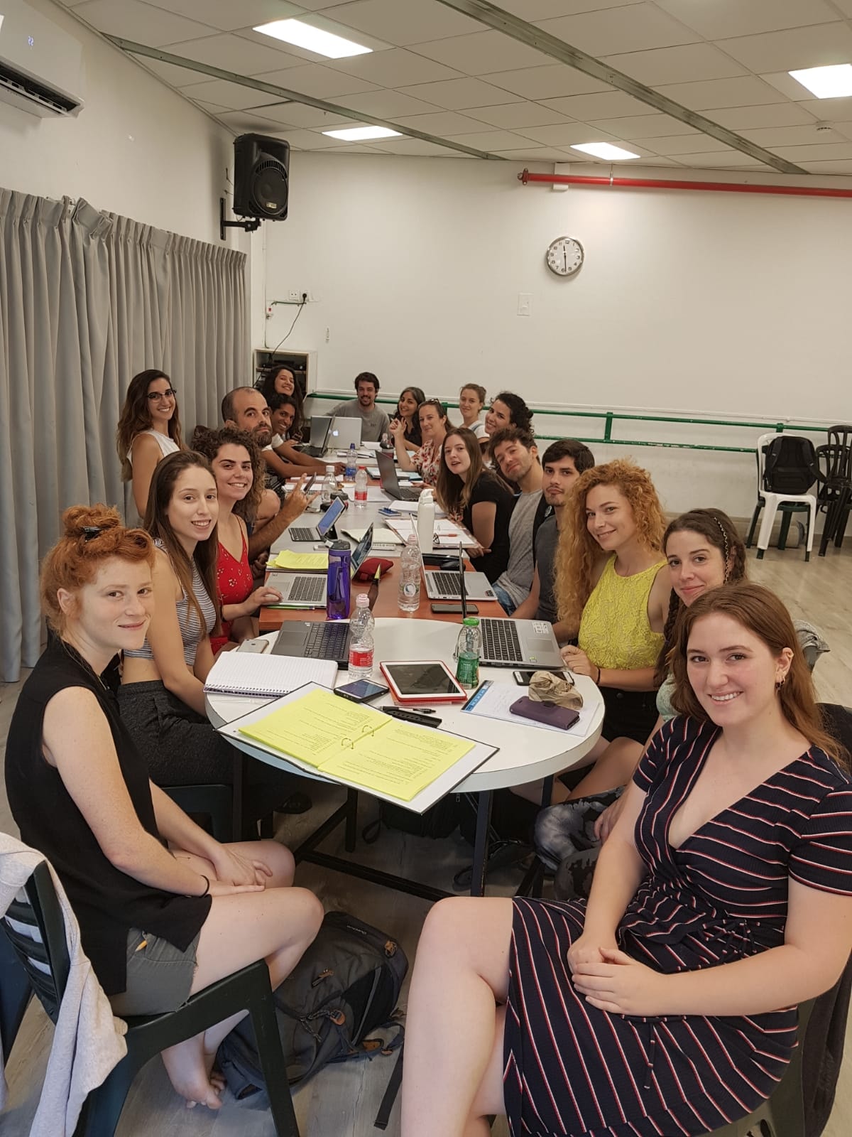 קבוצה סביב שולחנות עם מחברות ומחשבים בסטודיו